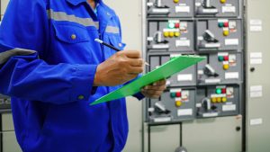 Engineer inspecting an electrical panel for compliance testing